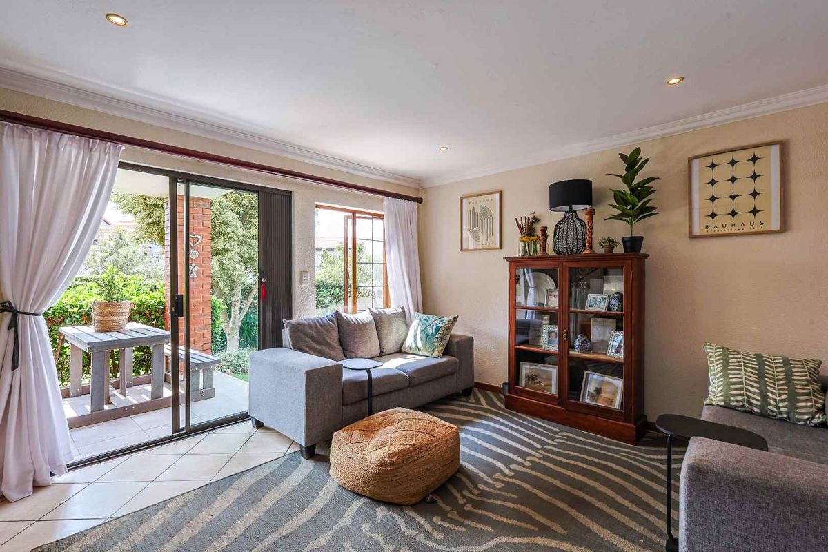 A bright living room featuring tiled flooring, recessed downlighting, and large sliding glass doors providing direct access to a covered patio area.