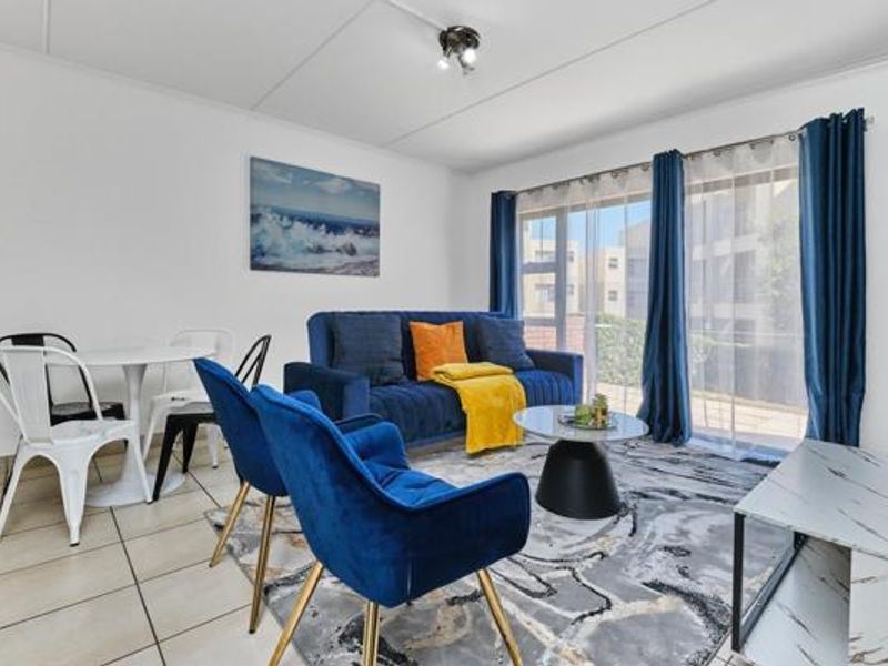A bright living room featuring tiled flooring and a large sliding glass door that provides natural light and access to the exterior.
