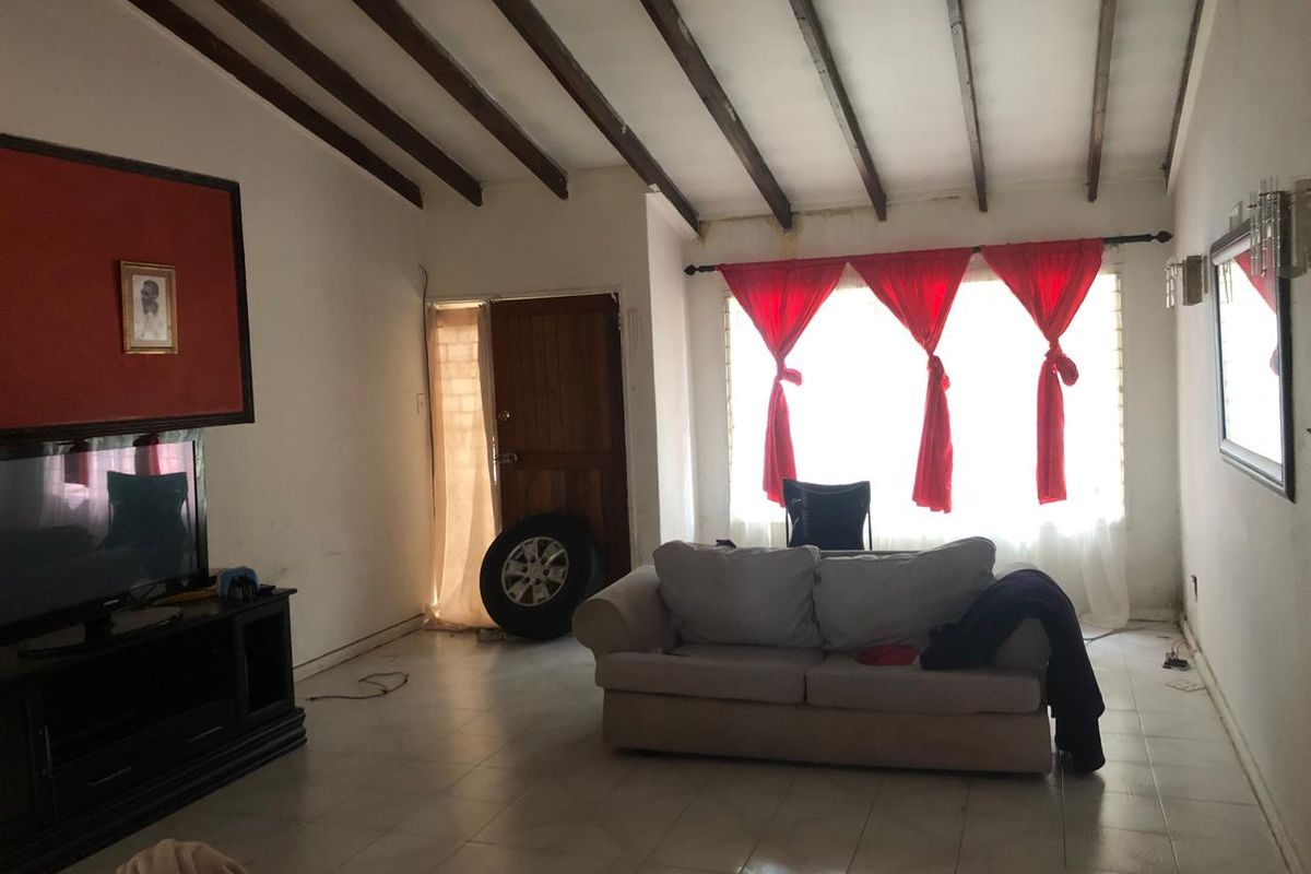 Living room featuring exposed timber ceiling beams, tiled flooring, and a timber entrance door, offering a rustic foundation for potential interior updates.