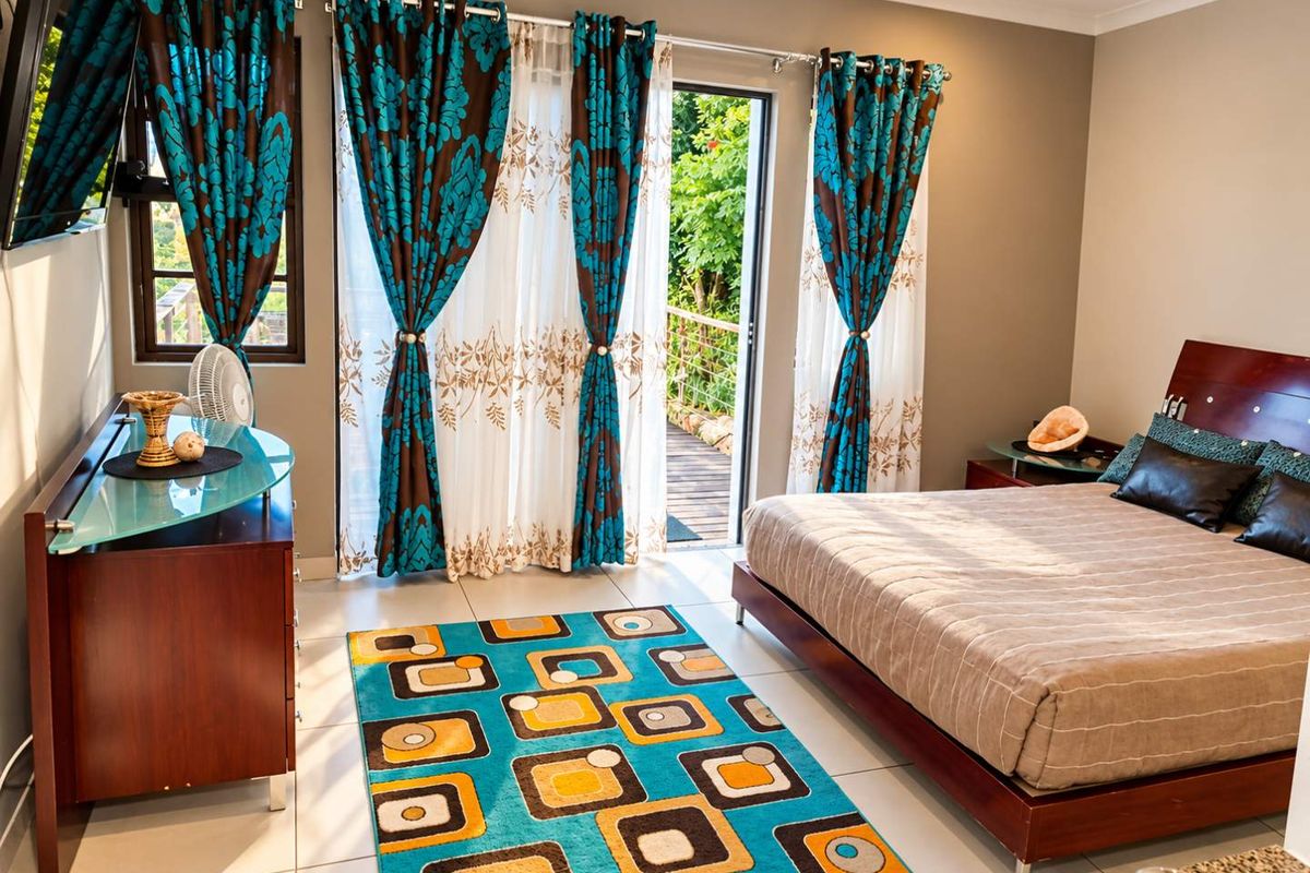 A well-lit bedroom featuring tiled flooring, recessed lighting, and a sliding glass door providing direct access to an outdoor balcony area.