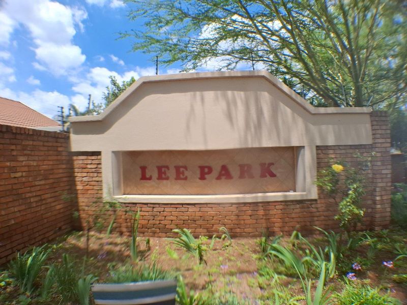 Entrance signage for Lee Park complex featuring a brick boundary wall and integrated security fencing.
