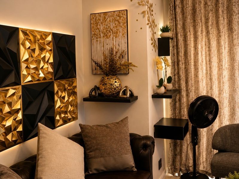 A cozy living room corner featuring decorative geometric wall paneling with integrated accent lighting and modern floating shelving.