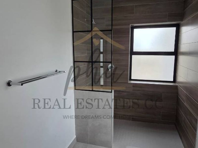 Modern bathroom featuring a walk-in shower with a stylish black-framed glass screen, contemporary wall and floor tiling, and high-quality fixtures.