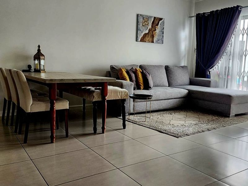 A well-maintained living area featuring neutral tiled flooring and a sliding glass door with security gate, providing access to the outdoor space.
