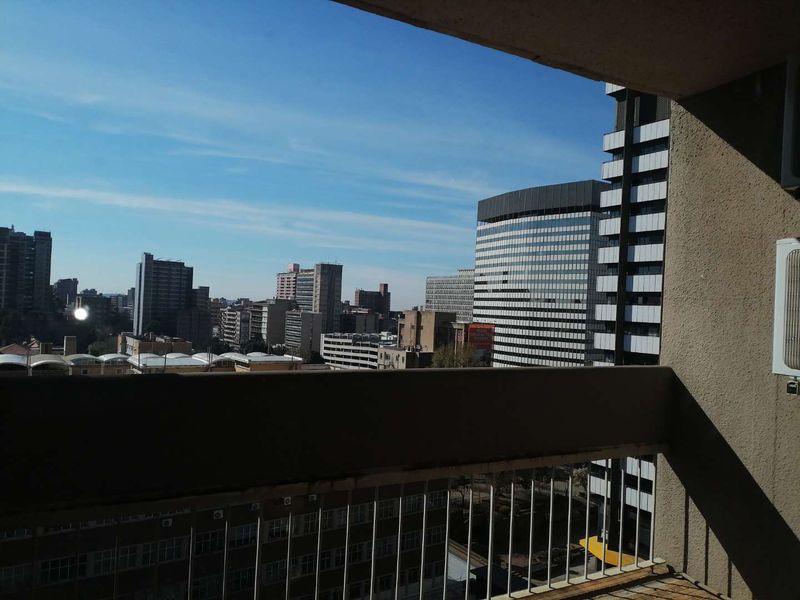 An elevated urban view from a balcony overlooking the surrounding city skyline and high-rise buildings.