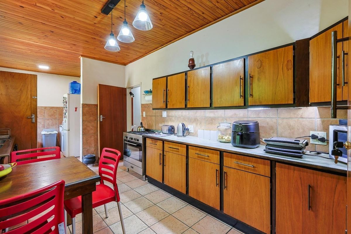 A functional kitchen featuring wooden cabinetry, tiled flooring, a tiled backsplash, and a timber-clad ceiling with pendant lighting.