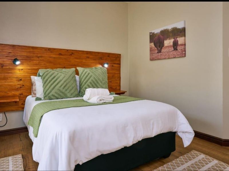 A cozy bedroom featuring a natural timber feature wall with integrated bedside shelving and durable laminate flooring.