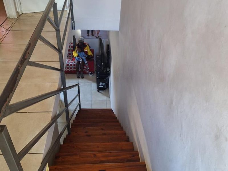 A staircase with wooden treads and a metal handrail leading down to a lower level landing area.