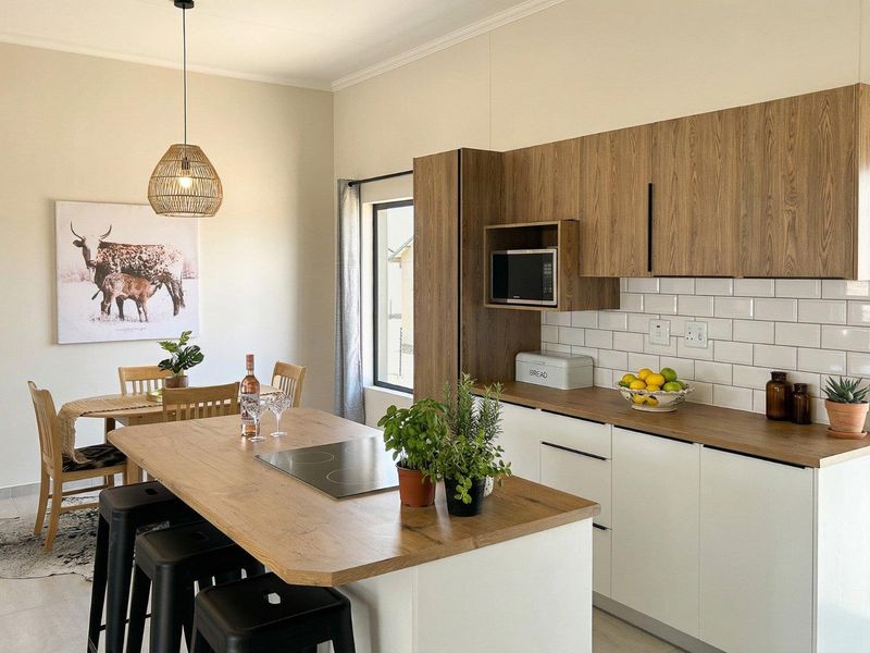 Modern open-plan kitchen featuring wood-look cabinetry, subway tile backsplash, and a central island with an integrated cooktop, seamlessly flowing into the dining area.