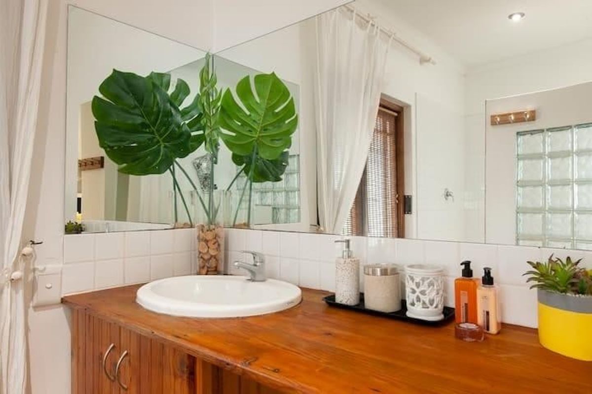 A bathroom vanity featuring a wooden countertop, a white drop-in basin, and a large wall-mounted mirror with glass block accents.