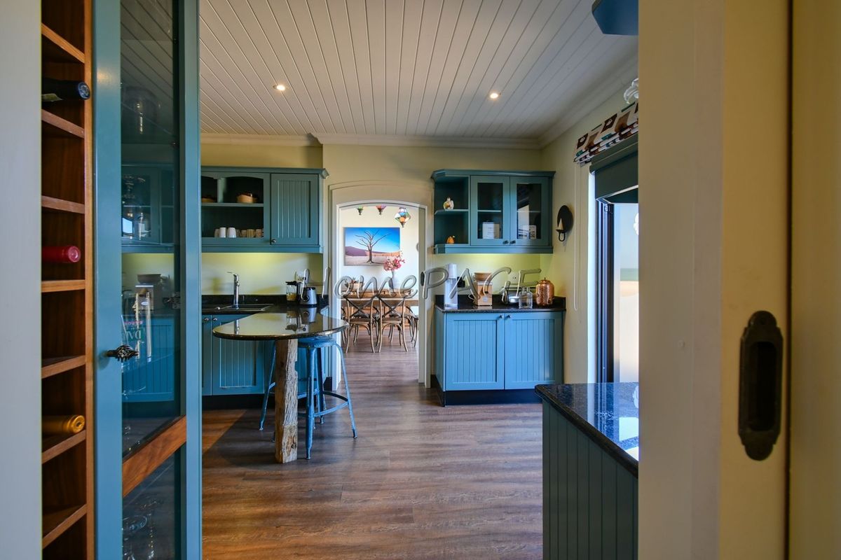 A well-appointed kitchen featuring blue cabinetry, granite countertops, and a built-in wine rack, with a seamless transition to the adjacent dining area.