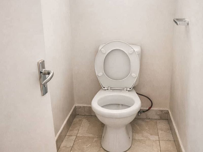 A compact, functional bathroom featuring a standard toilet and neutral tiled flooring.