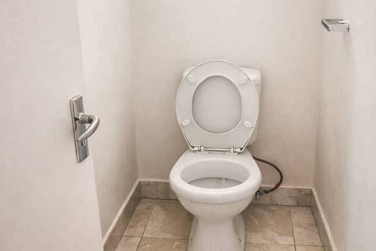 A compact, functional bathroom featuring a standard toilet and neutral tiled flooring.