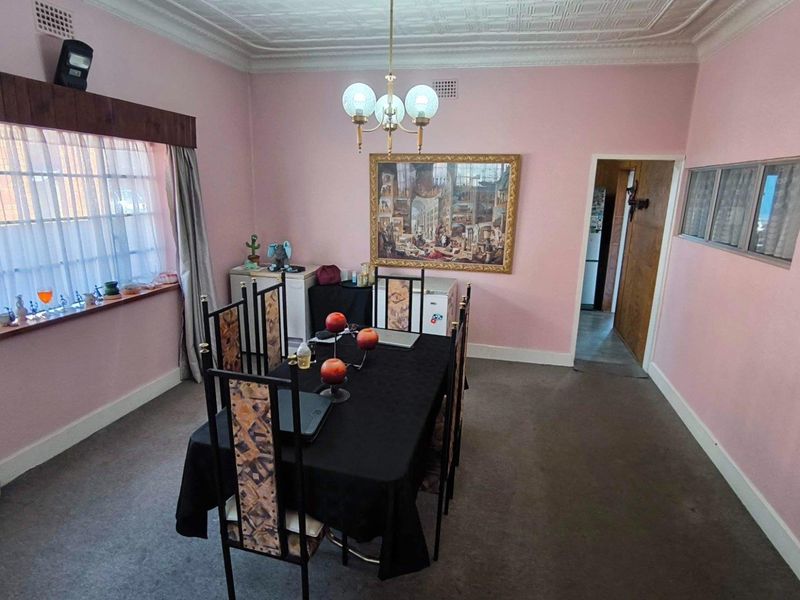 A dining room featuring an ornate pressed metal ceiling, cornicing, and a large window, providing a classic foundation for modern updates.