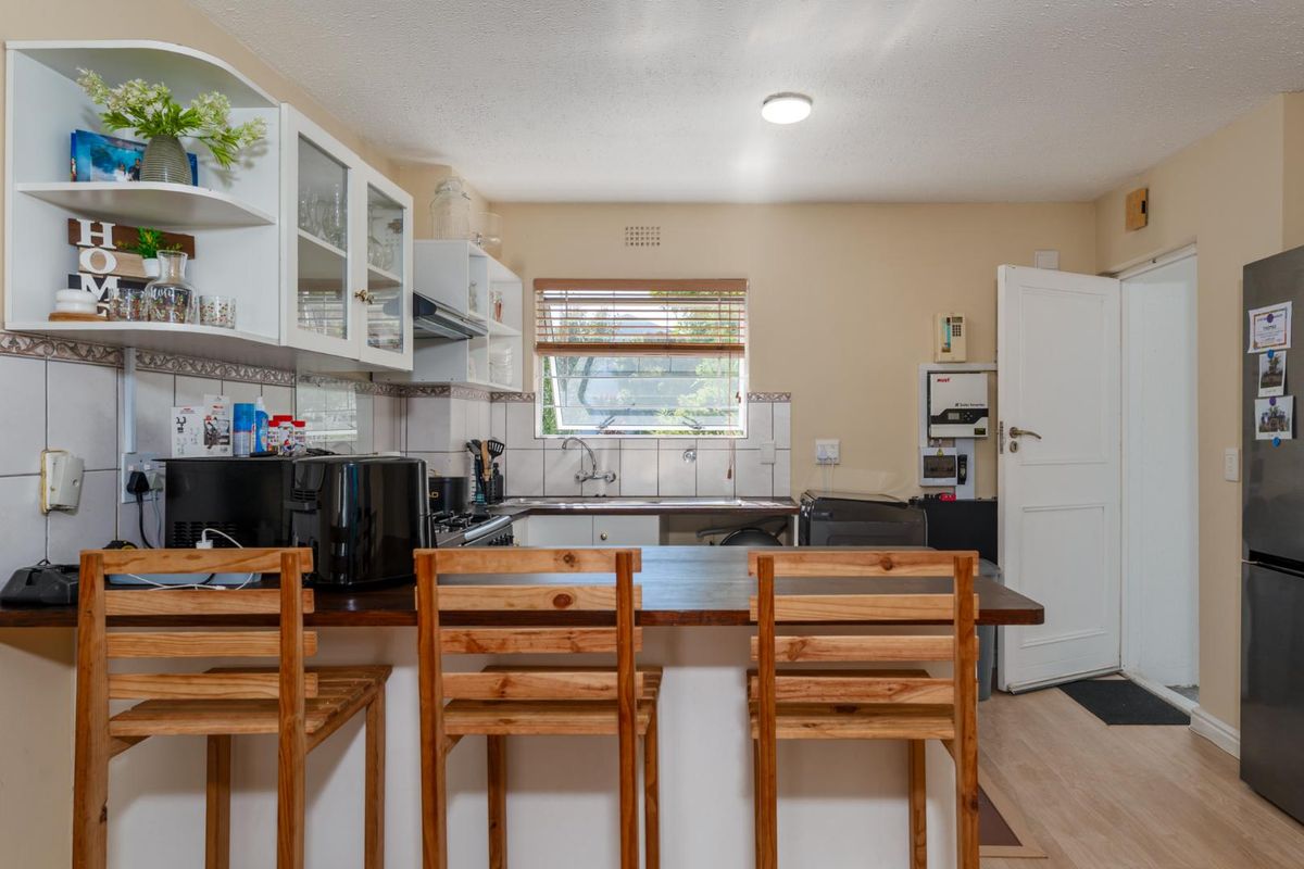Functional kitchen featuring a breakfast bar, built-in cabinetry, tiled backsplash, and direct access to an exterior door.