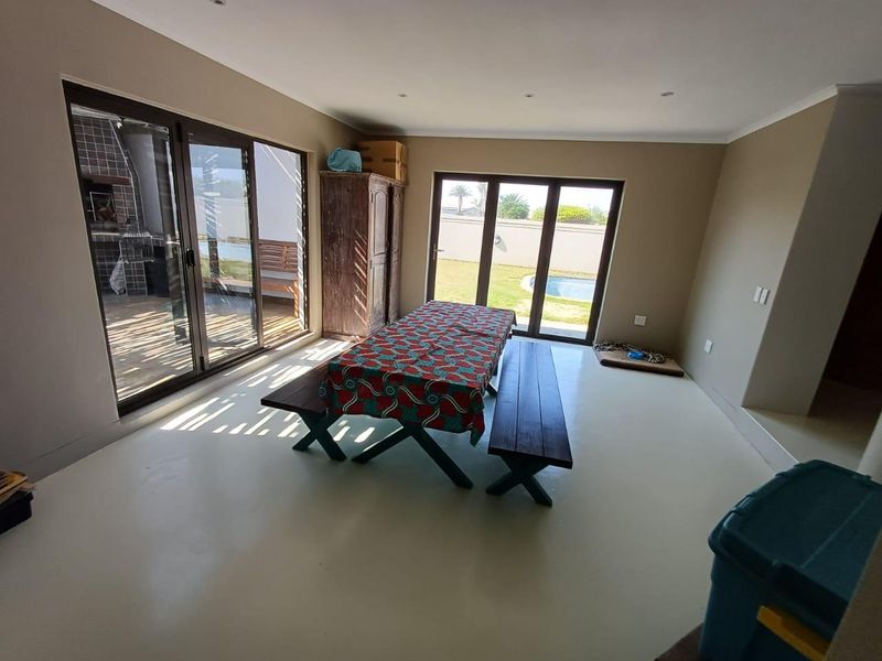 Spacious living area featuring smooth epoxy flooring and large sliding glass doors that provide seamless access to the outdoor patio and pool area.