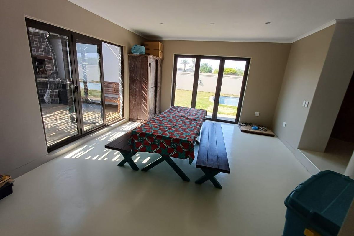 Spacious living area featuring smooth epoxy flooring and large sliding glass doors that provide seamless access to the outdoor patio and pool area.