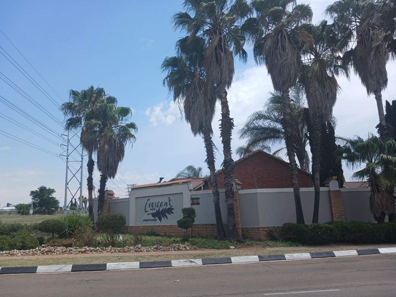 Street view of the Crescent Wood Country Estate entrance, featuring a brick and rendered perimeter wall with integrated estate signage and electric fencing.