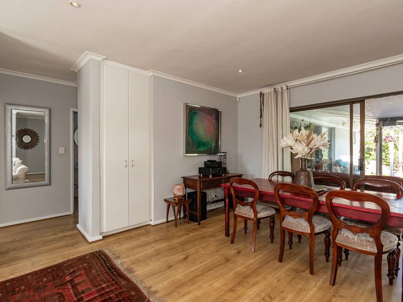 A well-maintained dining room featuring laminate flooring, built-in storage cabinetry, and large sliding glass doors providing access to the outdoor patio area.