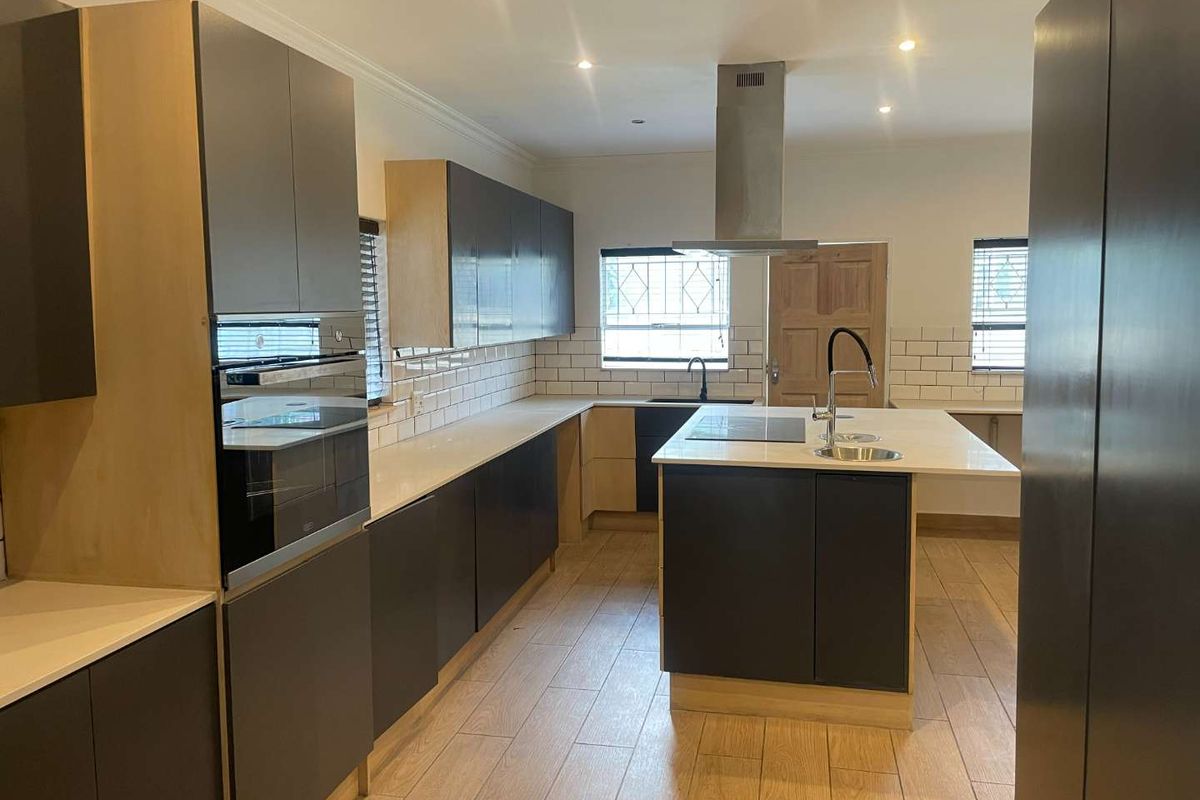 Modern kitchen featuring a central island, built-in oven, extractor fan, quartz countertops, and subway tile backsplash with wood-look tile flooring.