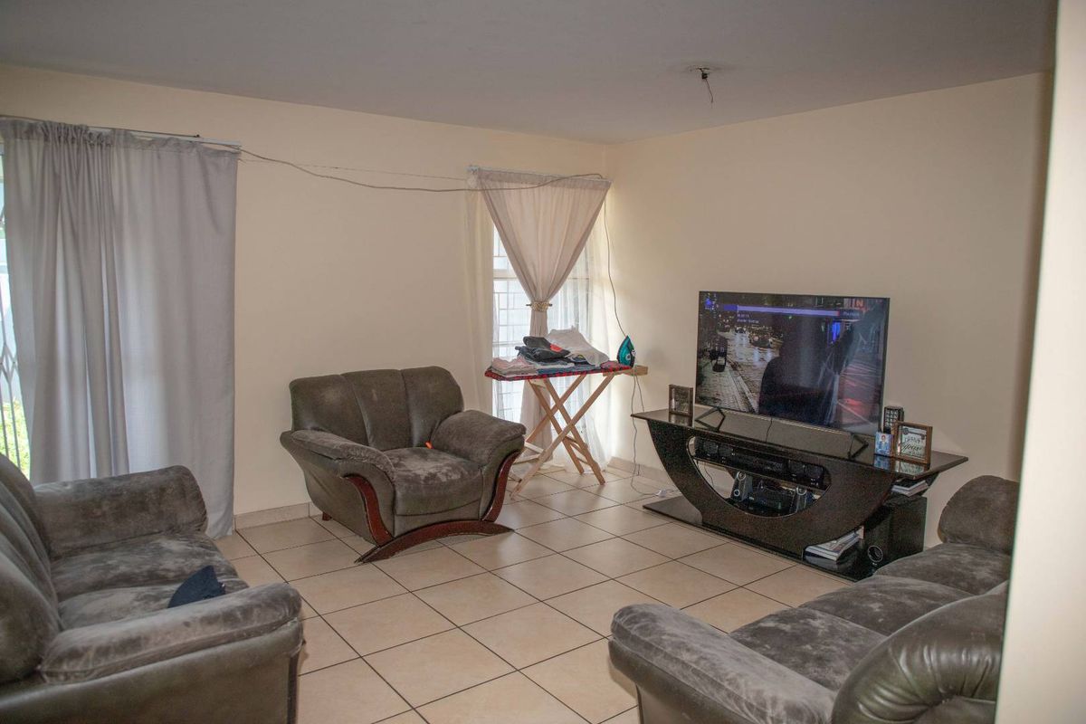 A living room featuring tiled flooring and natural light from a window, providing a functional space for relaxation.