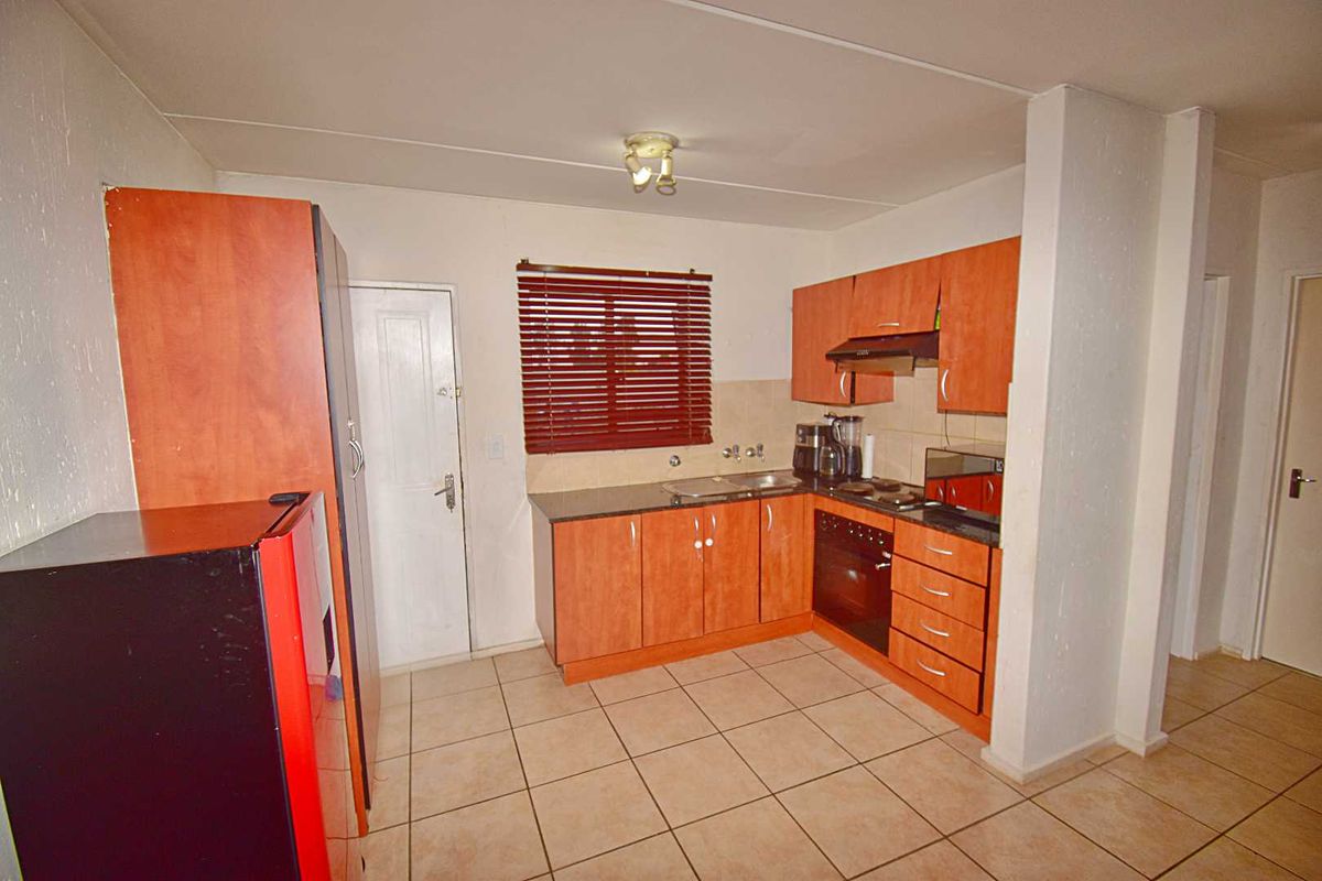 A functional kitchen featuring wood-finish cabinetry, dark countertops, a built-in oven, and tiled flooring, offering a practical layout for daily meal preparation.