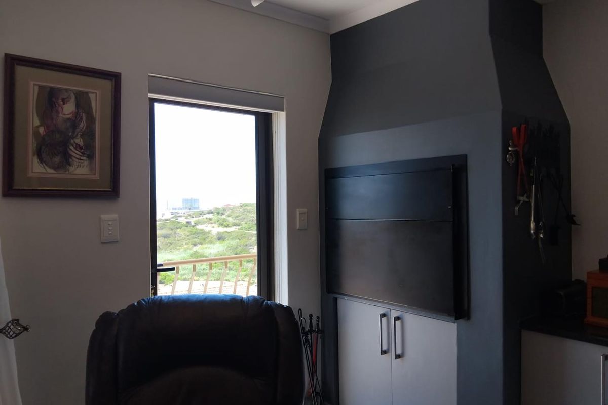 A living area featuring a built-in fireplace with a dark feature wall and access to an outdoor balcony with scenic views.