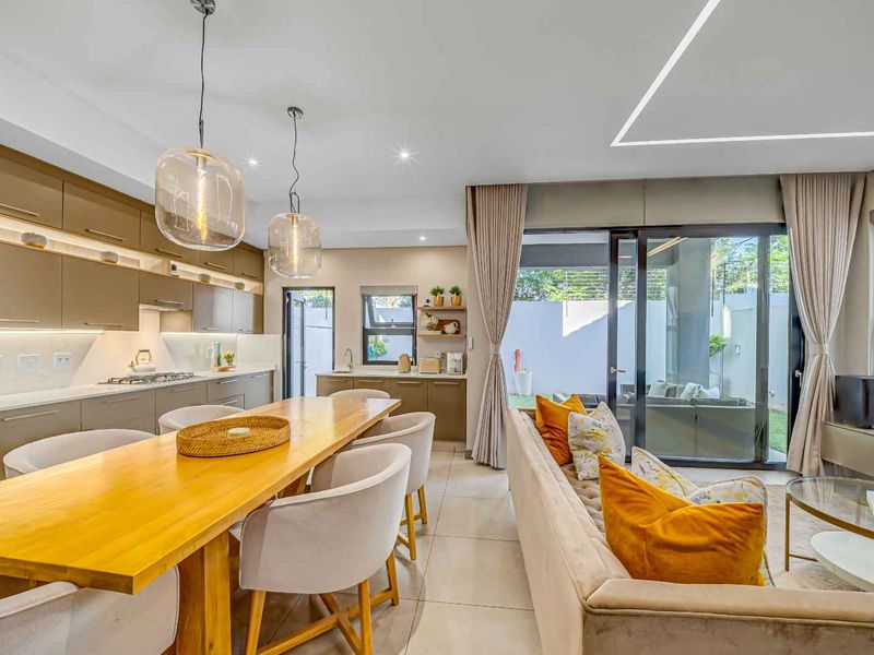 Modern open-plan living and kitchen area featuring sleek cabinetry, integrated appliances, tiled floors, and seamless access to the outdoor patio through sliding glass doors.