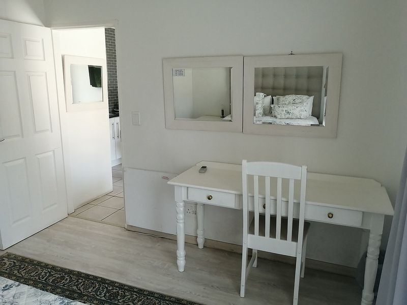 A bedroom interior featuring light-toned laminate flooring and a doorway leading to an adjacent tiled area.