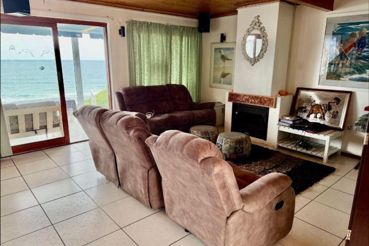 A living room featuring a built-in fireplace, tiled flooring, and sliding glass doors that open to a scenic ocean view.
