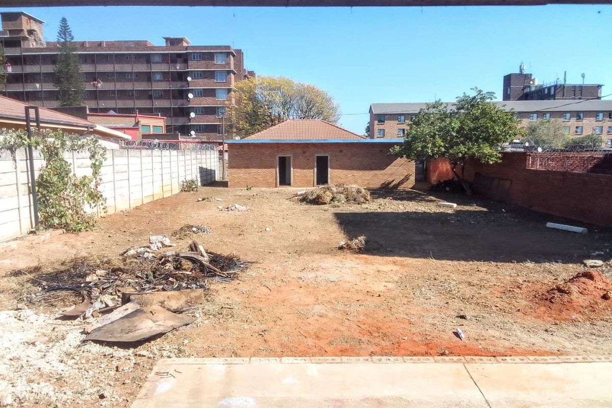A spacious rear yard area featuring a brick outbuilding, perimeter walling, and significant potential for landscaping or development.