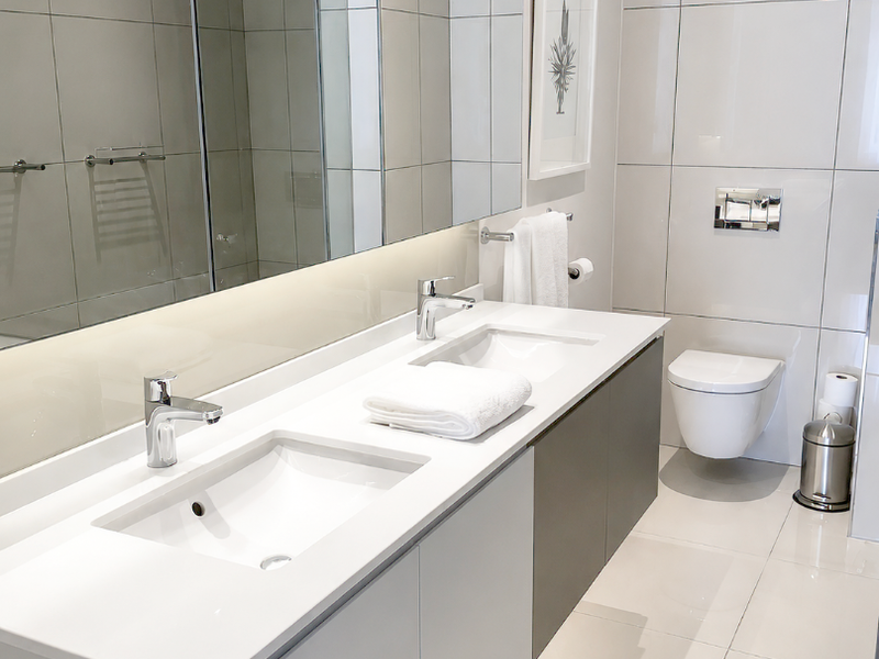 Modern bathroom featuring a sleek double vanity, wall-mounted toilet, large mirror, and high-quality tiled finishes throughout.