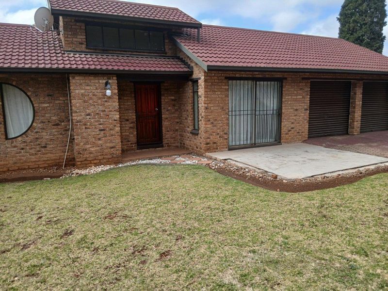Front view of a face brick house featuring a tiled roof, integrated garage, and a small concrete patio area.