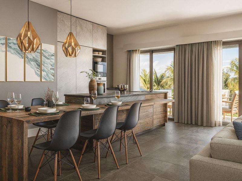 Modern open-plan living area featuring a sleek kitchen with integrated appliances, stone-look cabinetry, and seamless access to a private balcony.