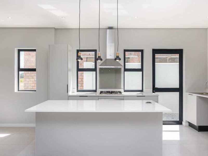 Modern kitchen featuring a central island with quartz countertops, gas hob, extractor fan, and sleek built-in cabinetry in a bright, open-plan layout.