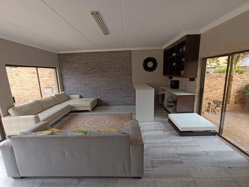 Spacious living area featuring a built-in bar, stone-cladding feature wall, and direct access to the outdoor area through sliding glass doors.