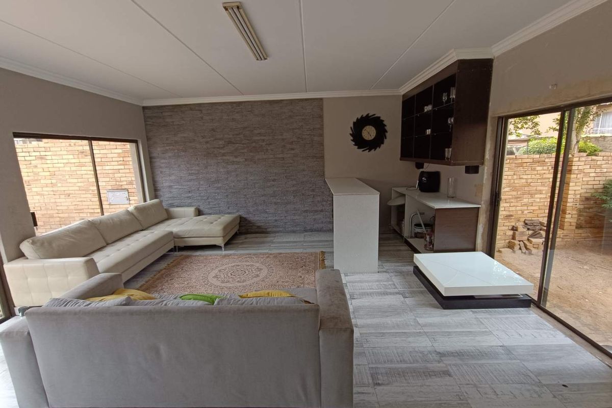 Spacious living area featuring a built-in bar, stone-cladding feature wall, and direct access to the outdoor area through sliding glass doors.