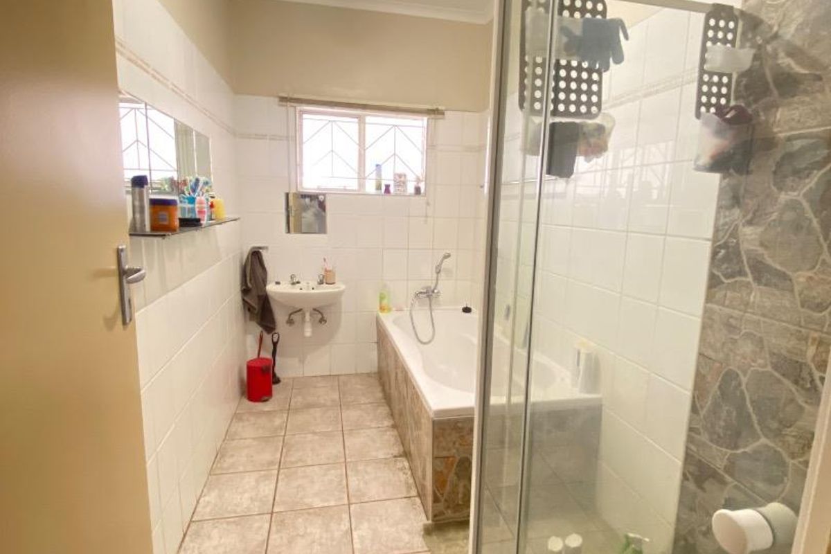 A functional bathroom featuring a shower enclosure, bathtub, and pedestal basin with tiled finishes, requiring some cosmetic updates to the ceiling and surfaces.