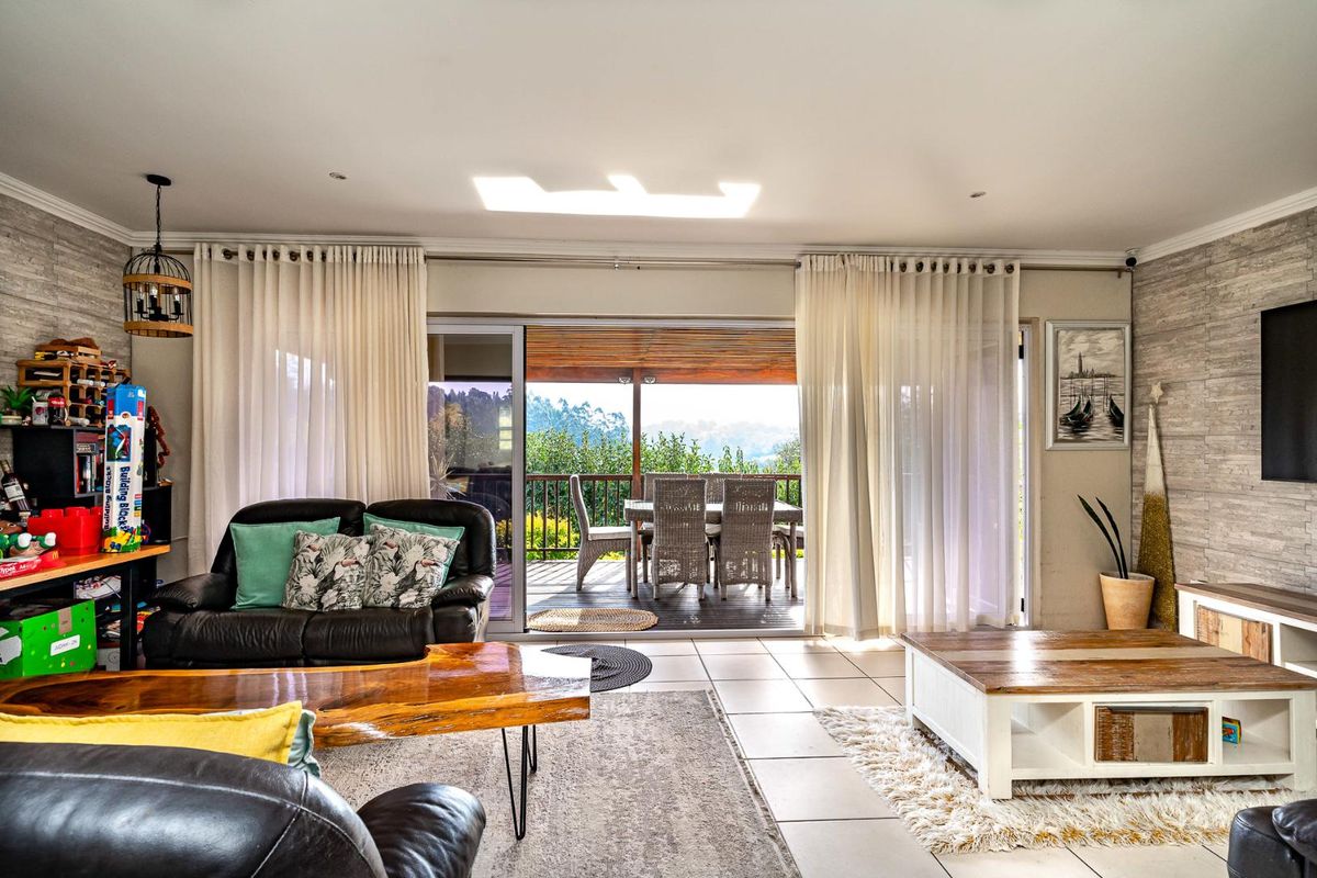 Spacious living room featuring tiled floors, a textured feature wall, and large sliding glass doors that open onto a covered patio with scenic views.