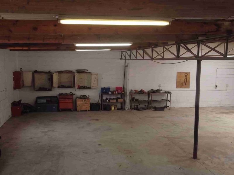 A spacious, open-plan utility or workshop area featuring exposed timber beams, concrete flooring, and industrial steel structural elements.