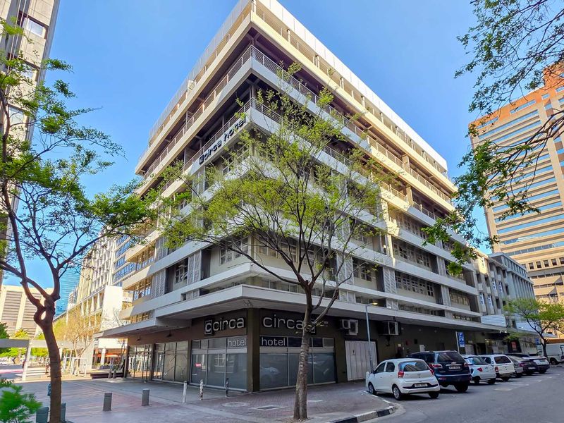 Exterior view of a multi-story apartment building featuring balconies with metal railings and ground-floor commercial frontage.