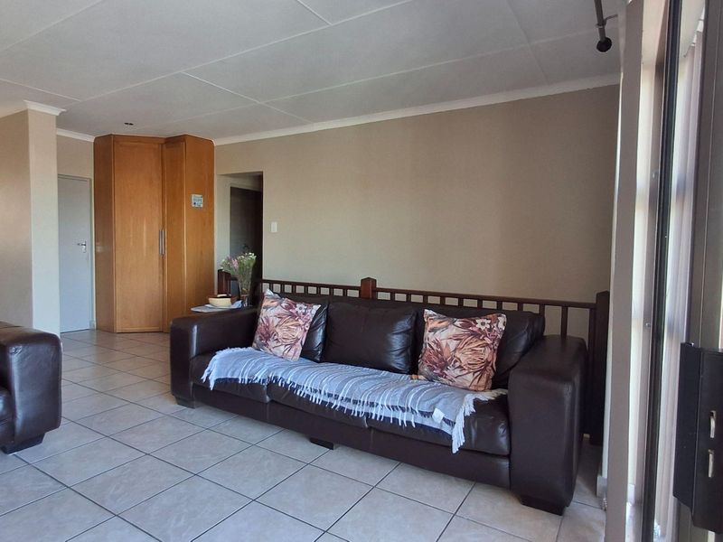 Spacious living area featuring neutral tiled flooring, a built-in storage cupboard, and large sliding glass doors providing access to the exterior.