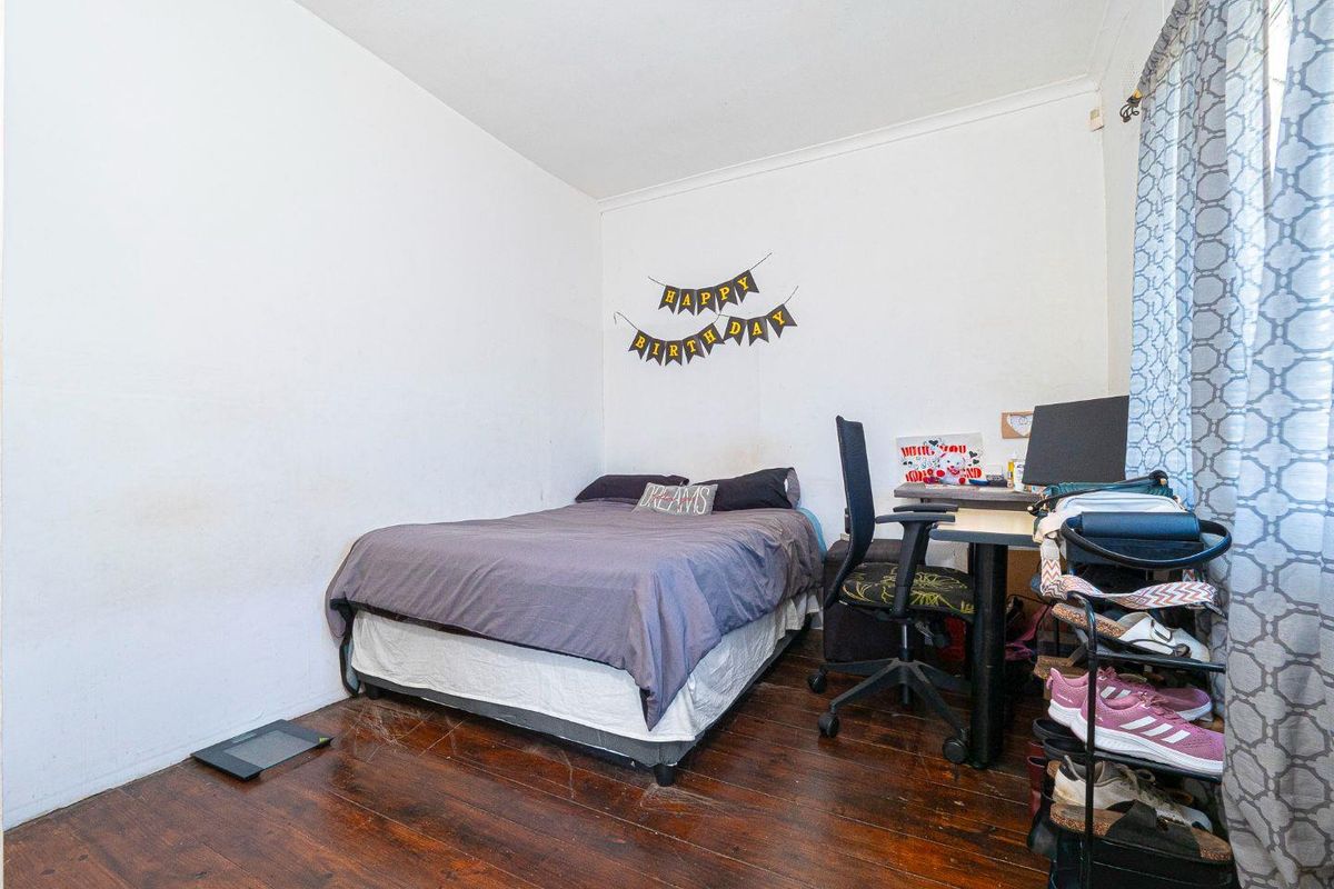 A functional bedroom featuring dark hardwood flooring and neutral walls, providing a blank canvas for potential interior updates.