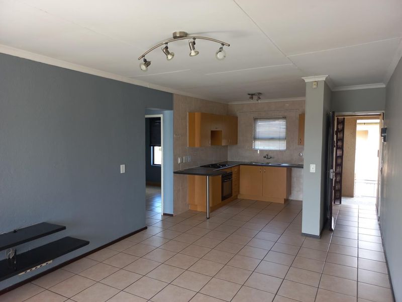 Open plan living and kitchen area featuring tiled floors, built-in cabinetry, and integrated oven, offering a functional layout ready for modern updates.