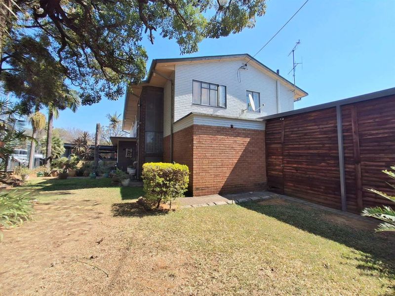 Rear view of the property featuring a brick and timber facade, sliding windows, and a private garden area with a timber boundary fence.