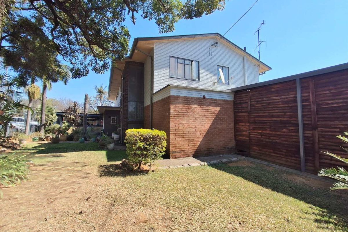 Rear view of the property featuring a brick and timber facade, sliding windows, and a private garden area with a timber boundary fence.