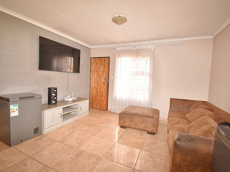 A living room featuring tiled flooring, a coved ceiling, and a timber door, providing a functional space for relaxation.