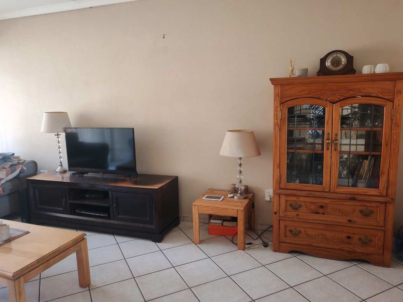A living room area featuring neutral wall finishes and tiled flooring, providing a functional space for relaxation.