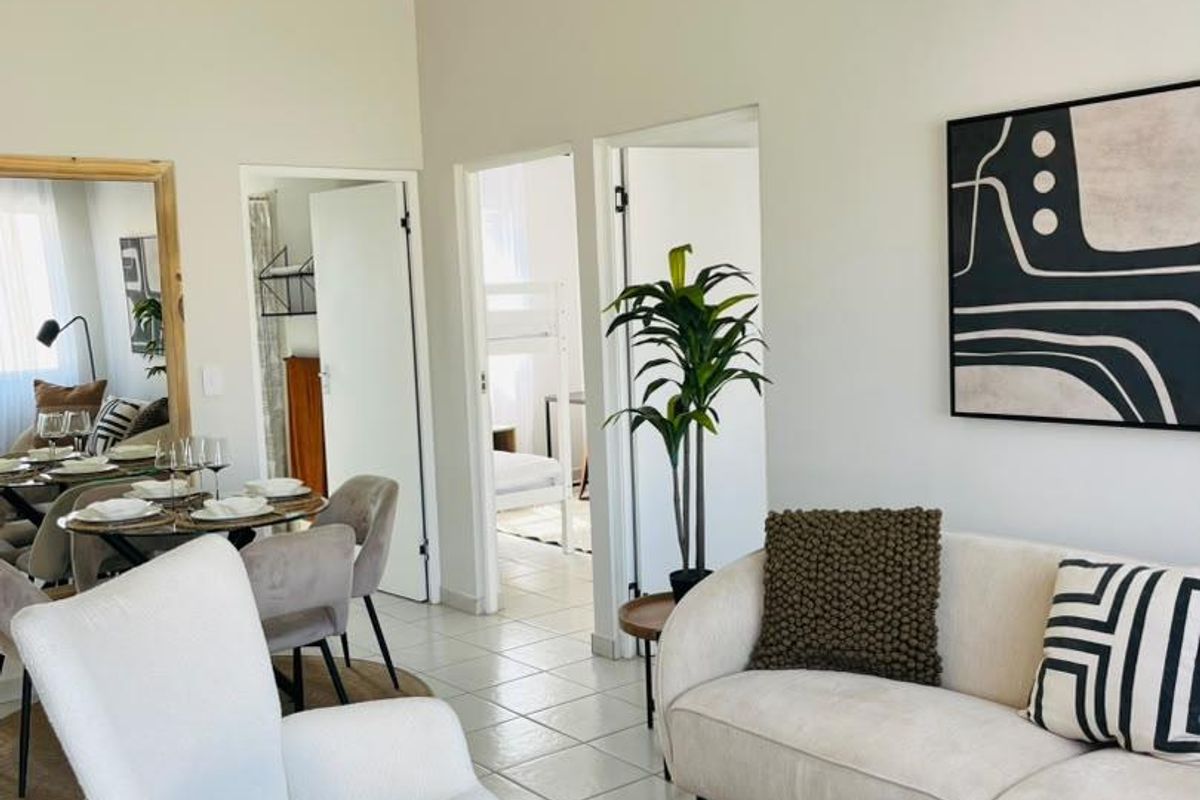 A bright and airy living room featuring tiled flooring, a vaulted ceiling, and neutral wall finishes, providing a comfortable and well-maintained living space.