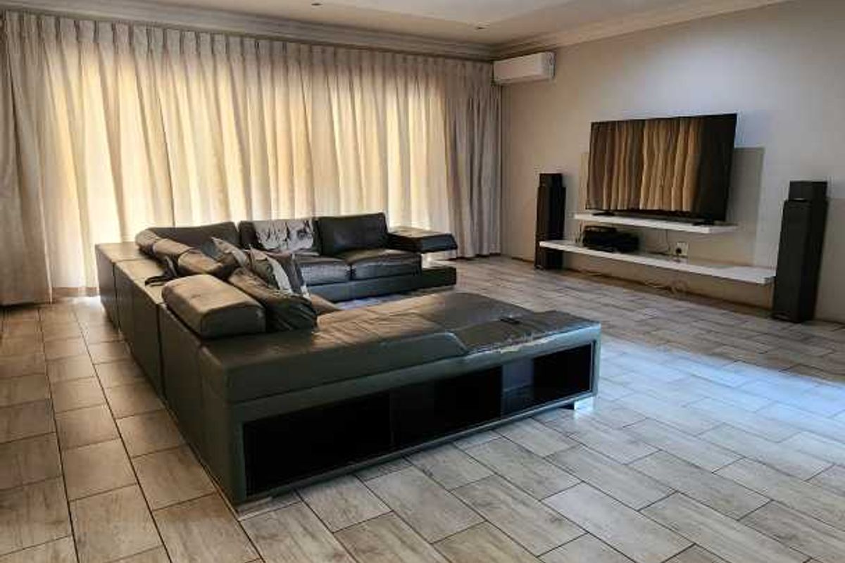 Spacious living room featuring wood-look tile flooring, a modern recessed ceiling feature with downlights, and a wall-mounted media shelf.